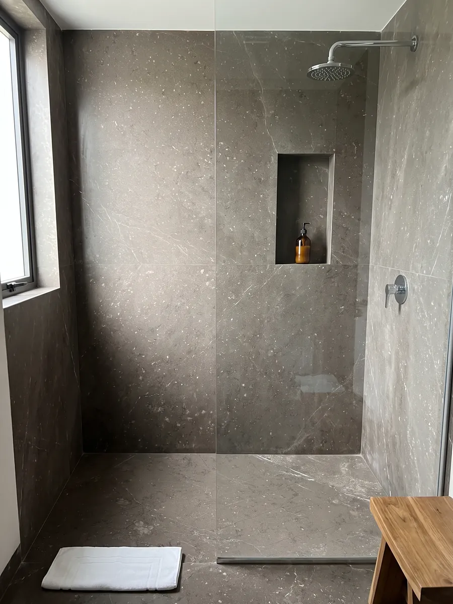 Ducha revestida con placas enteras de Mármol Gris Antracite con nicho empotrado: gris topo con pequeñas motas y apenas alguna veta blanca fina