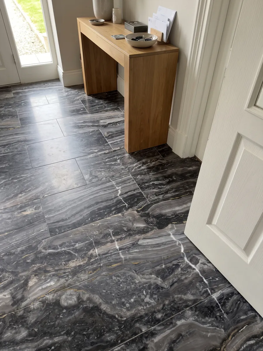 Piso de recibidor en placas grandes de mármol gris Arabescato Grigio Orobico con luz natural: gris antracita con ondas horizontales y algunas vetas blancas finas que lo cortan verticalmente