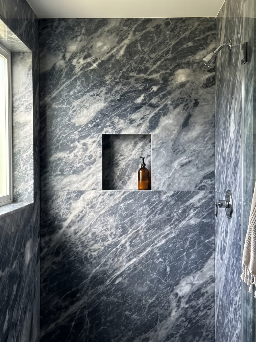 Ducha revestida con placas enteras de mármol gris Bardiglio Nuvolato con nicho empotrado: gris oscuro azulado con nubes y vetas blanquecinas difusas en diagonal