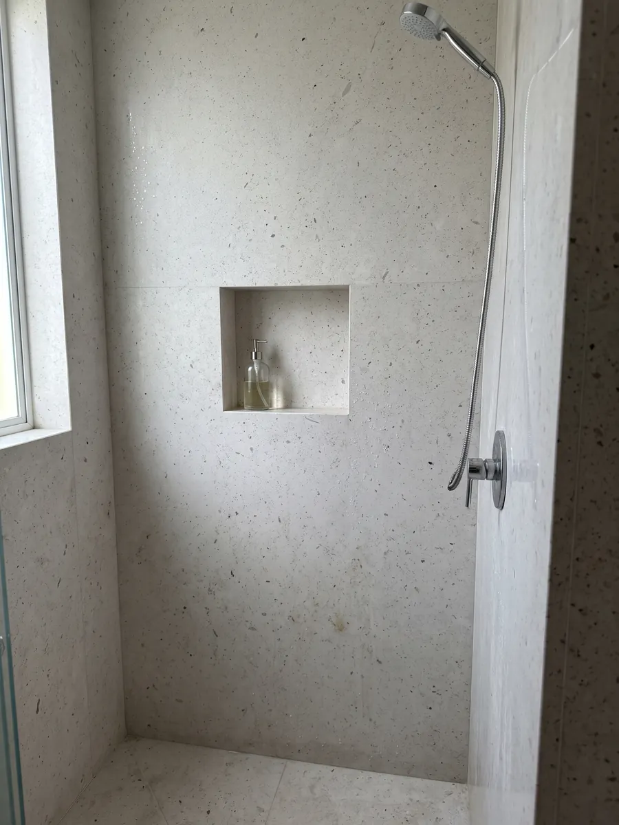 Ducha revestida con placas enteras de mármol gris Bianco Martel con nicho empotrado: gris claro liso con muchos puntos oscuros pequeños repartidos