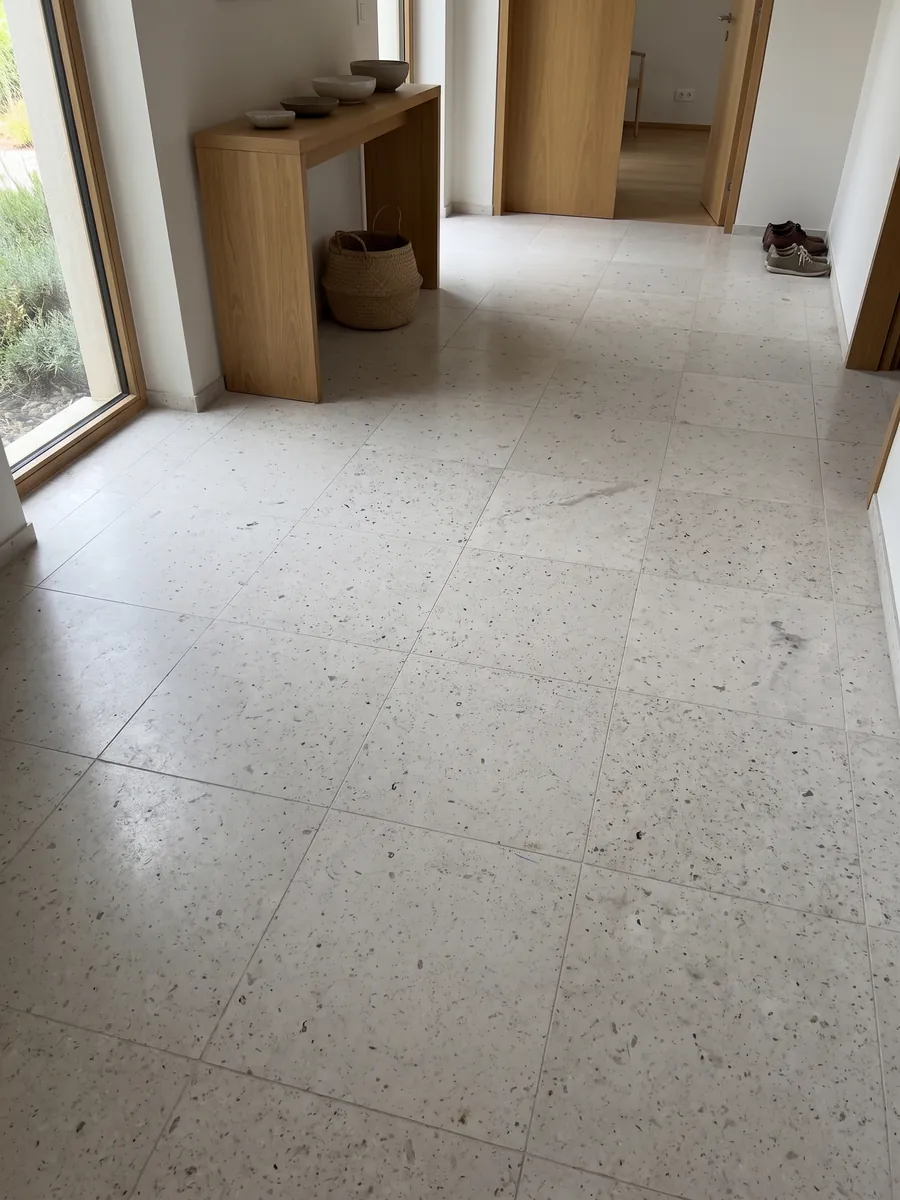 Piso de recibidor en placas grandes de mármol gris Bianco Martel con luz natural: gris claro liso con muchos puntos oscuros pequeños repartidos