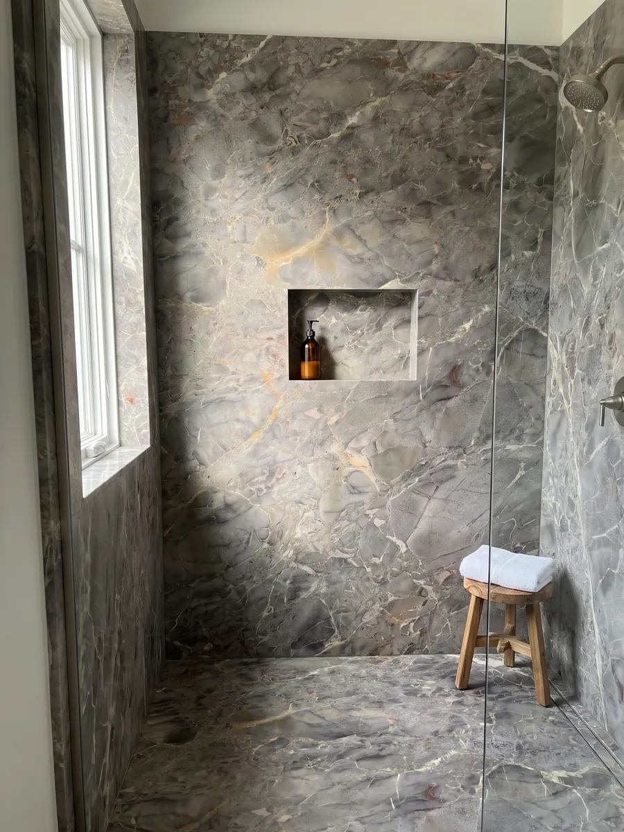 Ducha revestida con placas enteras de mármol gris Breccia di Versailles con nicho empotrado: gris pardo con fragmentos difusos, vetas claras finas y toques ocre
