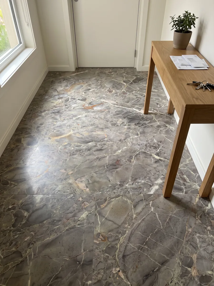 Piso de recibidor en placas grandes de mármol gris Breccia di Versailles con luz natural: gris pardo con fragmentos difusos, vetas claras finas y toques ocre