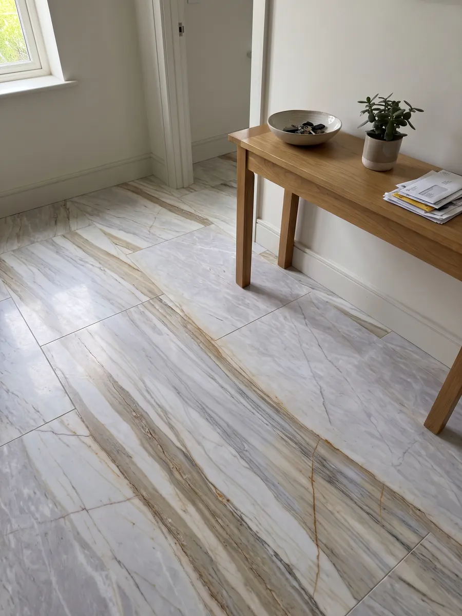 Piso de recibidor en placas grandes de mármol gris Calacatta Supreme con luz natural: gris lavanda claro con bandas beige diagonales y finas líneas ocre