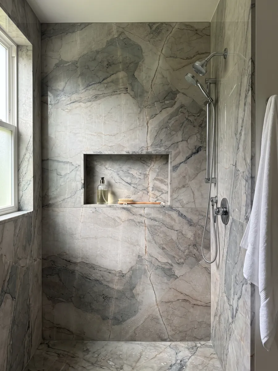 Ducha revestida con placas enteras de mármol gris Camouflage con nicho empotrado: fragmentos gris lavanda y azulado con vetas finas en patrón de mosaico