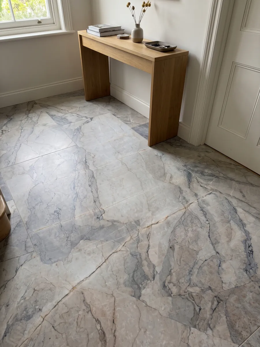 Piso de recibidor en placas grandes de mármol gris Camouflage con luz natural: fragmentos gris lavanda y azulado con vetas finas en patrón de mosaico