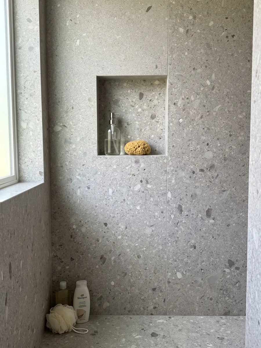 Ducha revestida con placas enteras de mármol gris Ceppo di Gré con nicho empotrado: gris claro con pequeños fragmentos beige y grises repartidos