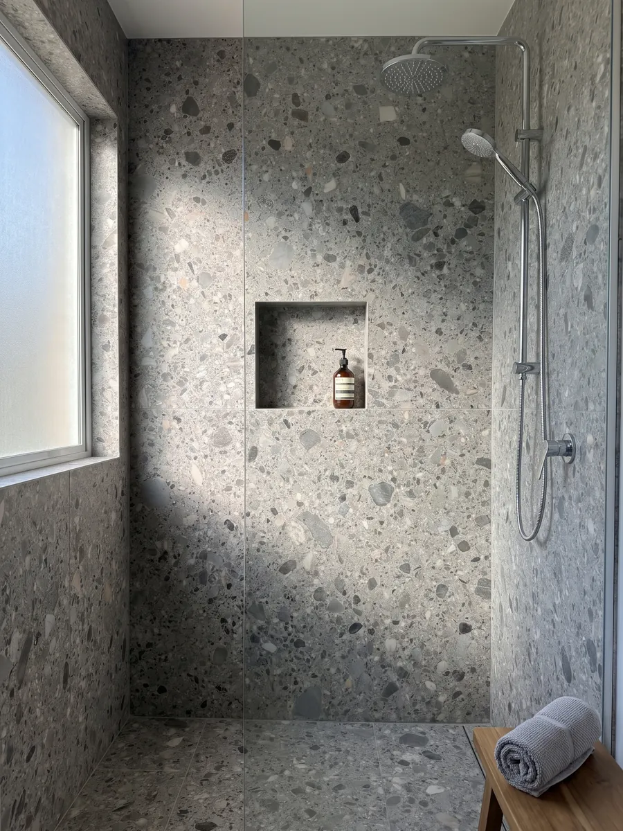 Ducha revestida con placas enteras de mármol gris Ceppo con nicho empotrado: matriz gris con cantos rodados grises, beige y negros de varios tamaños