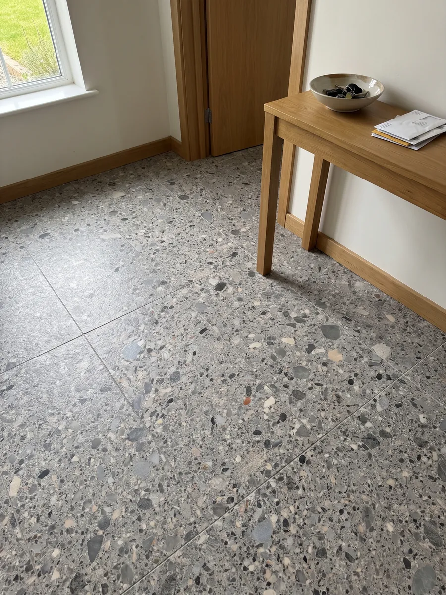 Piso de recibidor en placas grandes de mármol gris Ceppo con luz natural: matriz gris con cantos rodados grises, beige y negros de varios tamaños