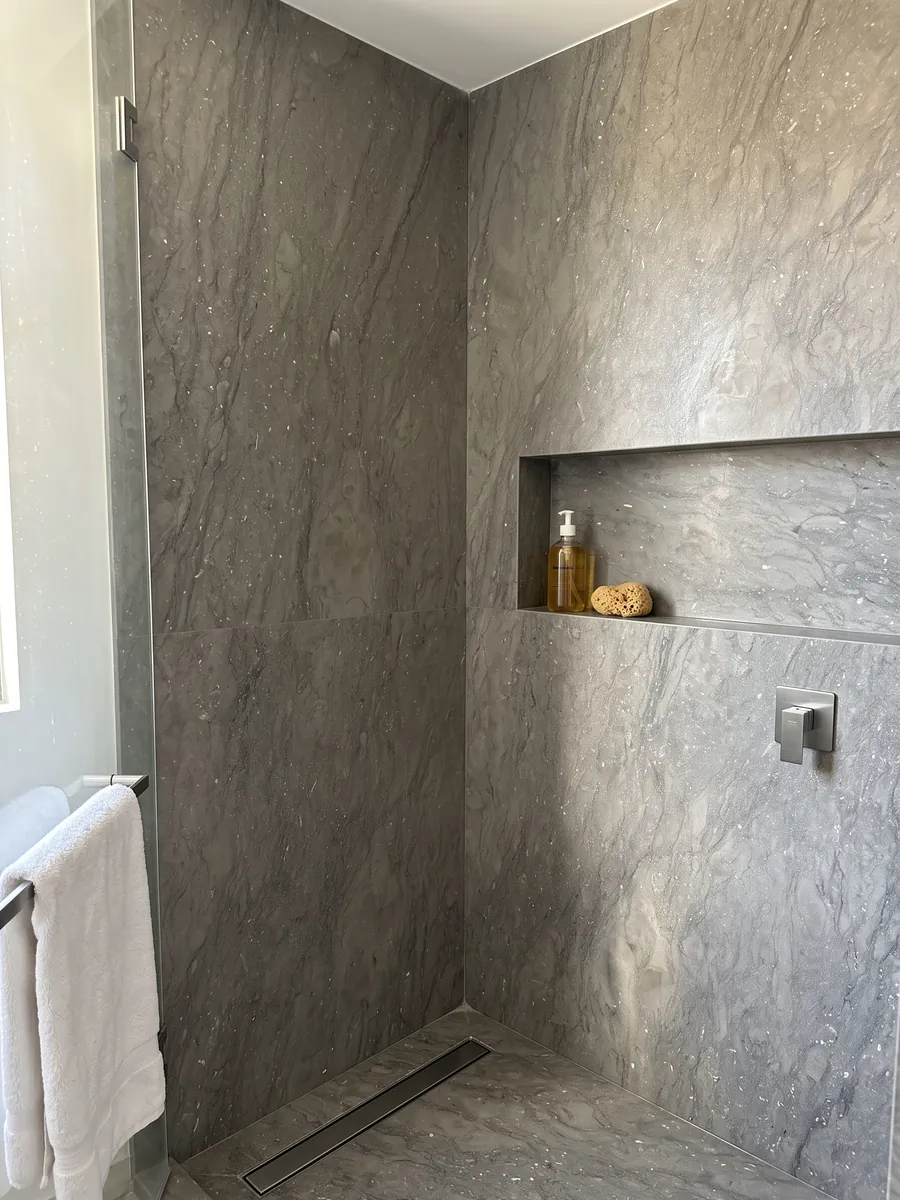 Ducha revestida con placas enteras de mármol gris Ebano con nicho empotrado: gris pardo uniforme con pequeños puntos claros brillantes