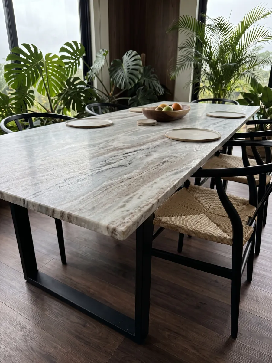 Mesa de comedor con cubierta de mármol gris Fantasy Brown sobre base de acero: nubes alargadas de blanco y gris con algunos trazos oscuros en diagonal