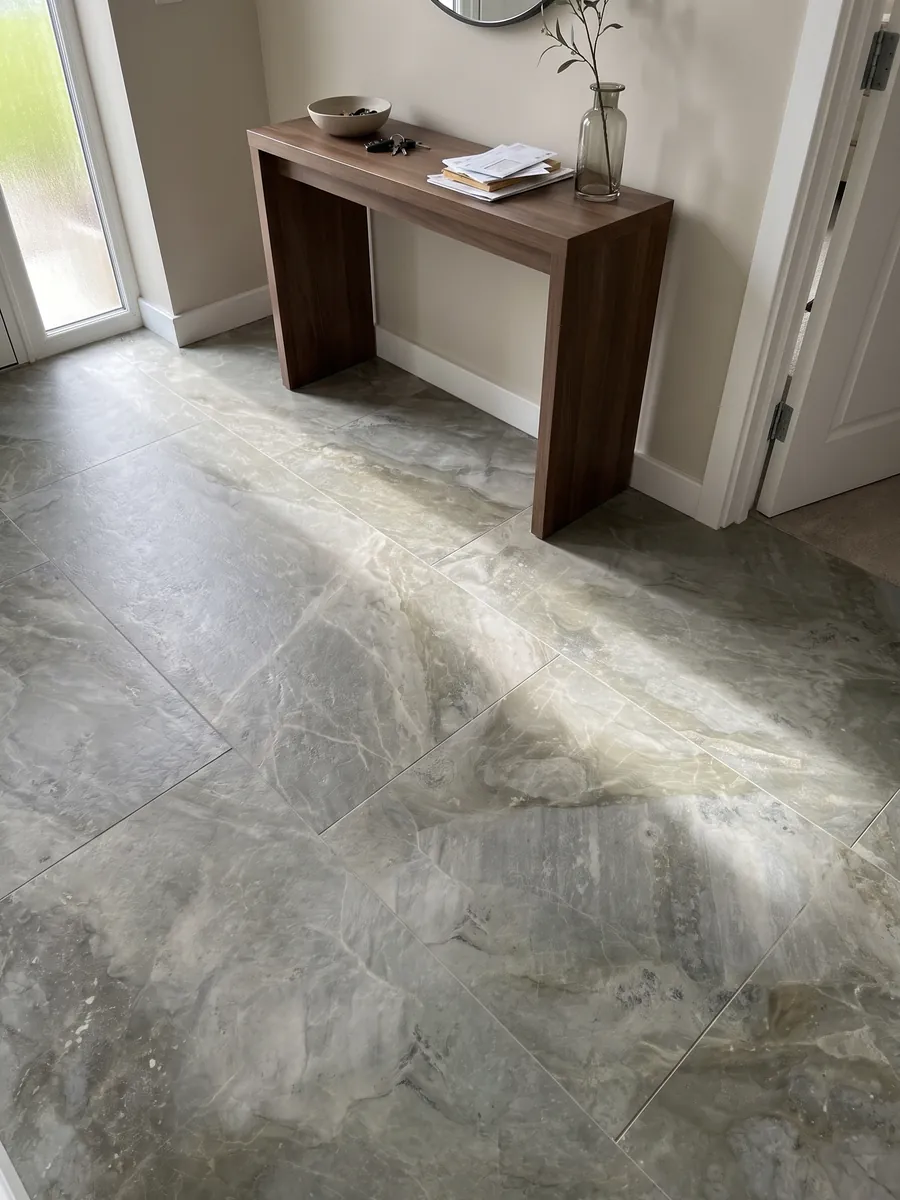 Piso de recibidor en placas grandes de mármol gris Fior di Bosco con luz natural: gris verdoso apagado con nubes tonales y vetas finas casi invisibles