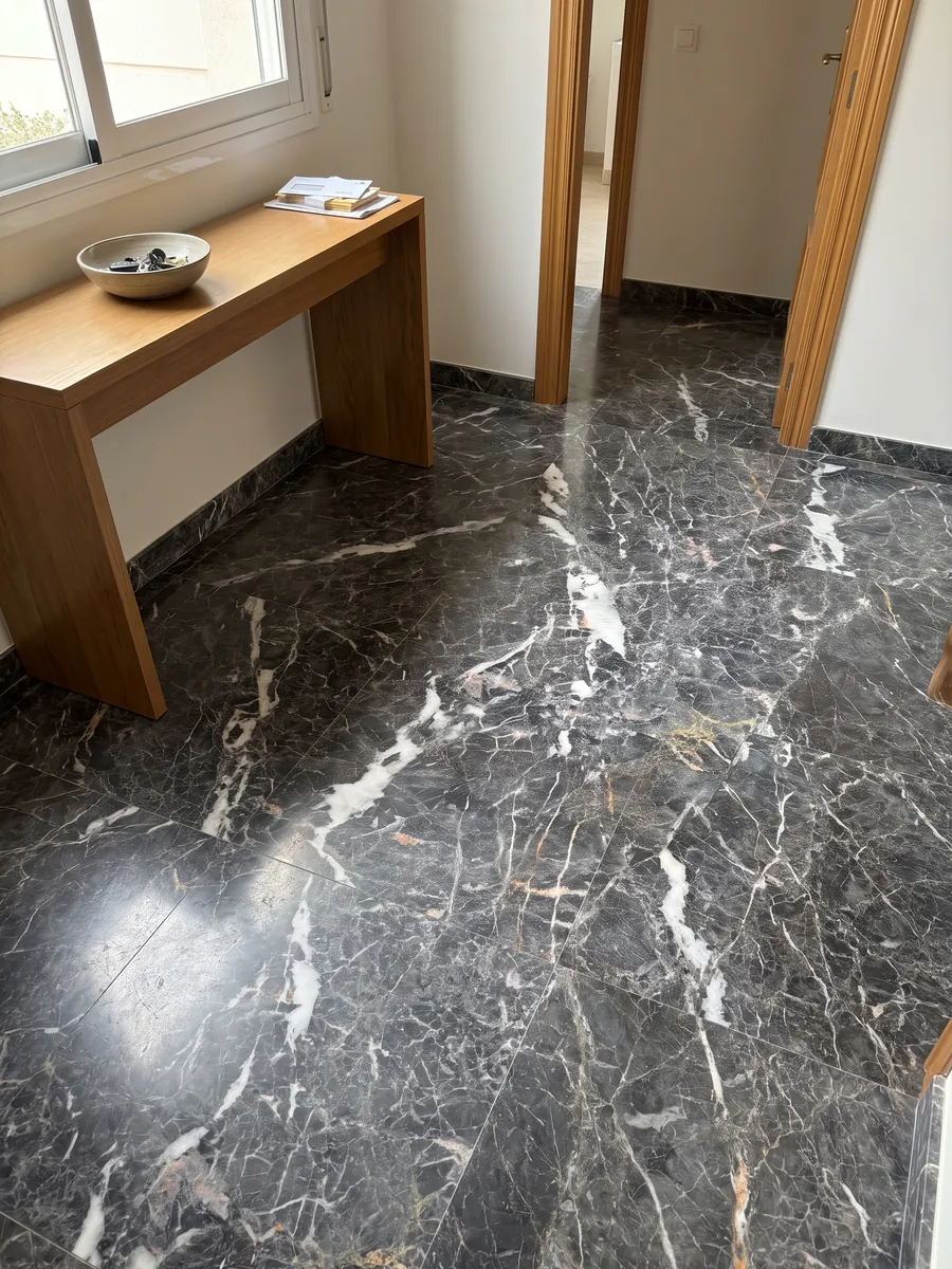 Piso de recibidor en placas grandes de mármol gris Grey Saint Laurent con luz natural: gris oscuro con manchas blancas alargadas y una red fina de vetas claras y doradas