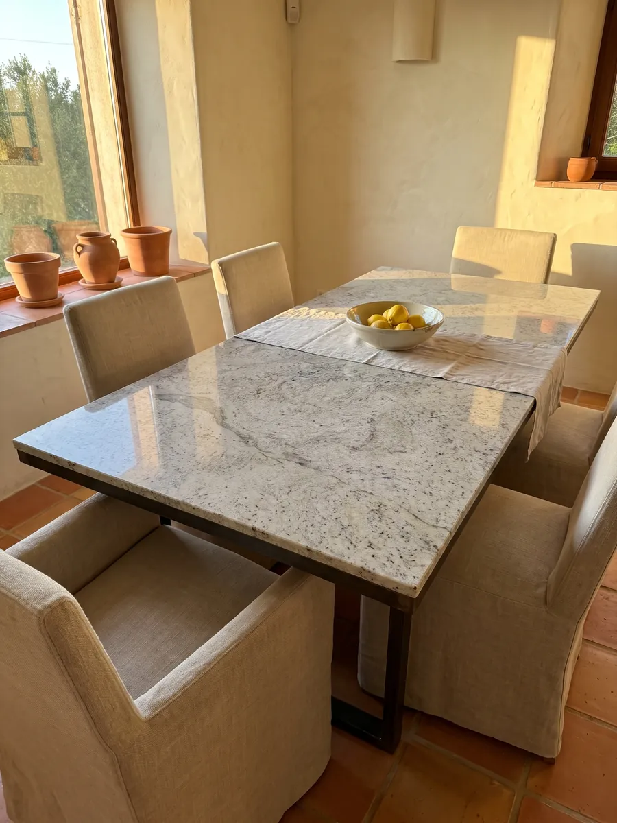 Mesa de comedor con cubierta de mármol gris Lemon Ice sobre base de acero: gris claro salpicado de motas oscuras, con aspecto parecido al granito