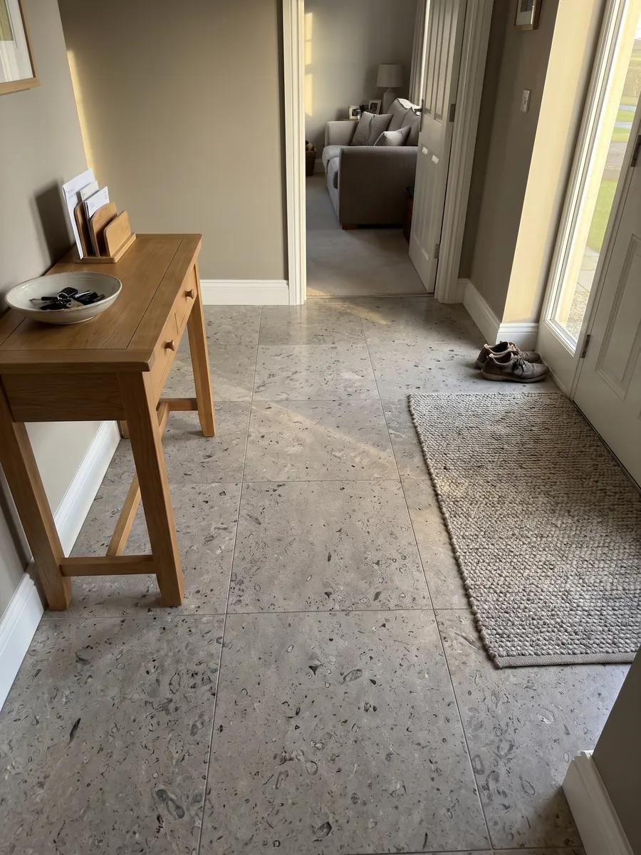 Piso de recibidor en placas grandes de mármol gris Lipica Fiorito con luz natural: gris beige con pequeñas figuras fósiles oscuras repartidas por toda la placa