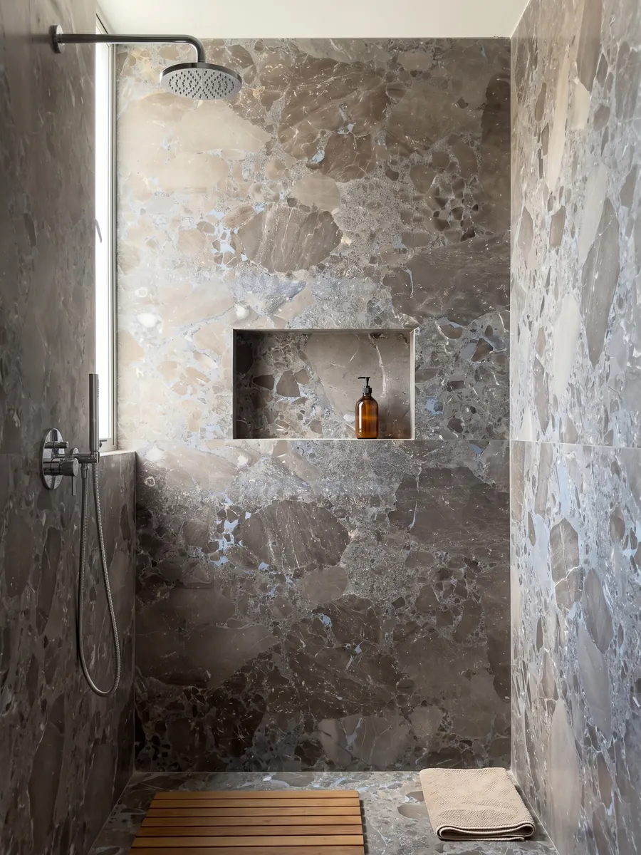 Ducha revestida con placas enteras de mármol gris Moon Grey con nicho empotrado: fragmentos angulosos grandes en marrón grisáceo unidos por una matriz gris azulada