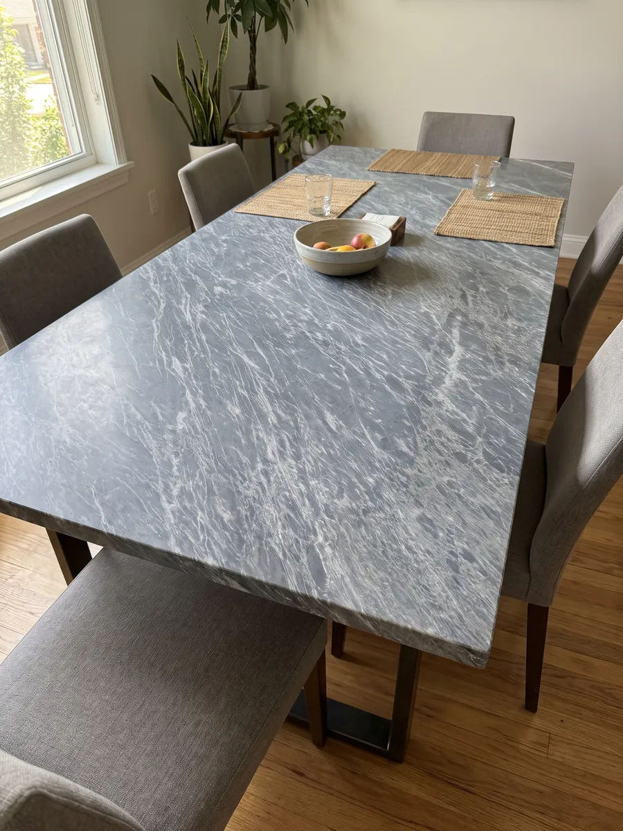 Mesa de comedor con cubierta de Mármol Gris Perla sobre base de acero: gris azulado cubierto de trazos blancos finos y paralelos en diagonal