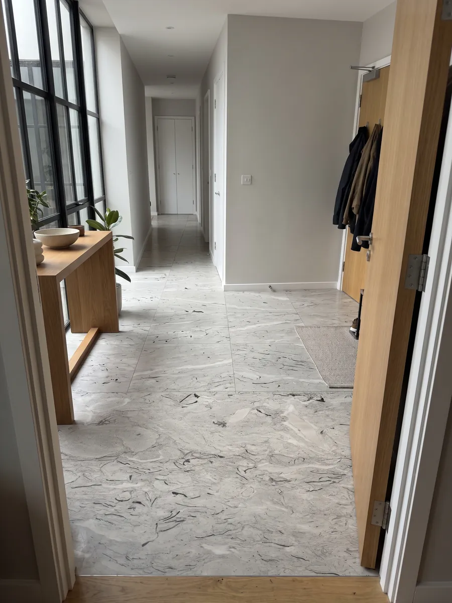 Piso de recibidor en placas grandes de mármol gris Repen con luz natural: gris claro con trazos negros curvos de fósiles y nubes horizontales