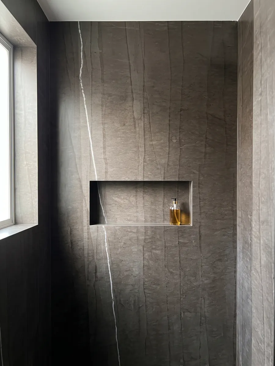 Ducha revestida con placas enteras de Mármol Gris Tao con nicho empotrado: café oscuro con líneas verticales tenues y una única veta blanca fina