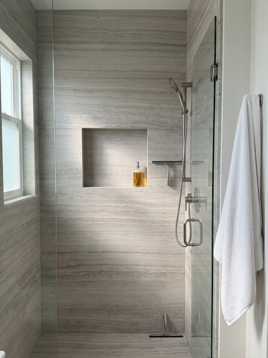 Ducha revestida con placas enteras de mármol gris White Wood con nicho empotrado: gris claro con líneas horizontales finas que imitan la fibra de la madera
