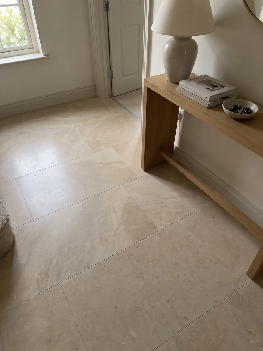 Piso de recibidor en placas grandes de Mármol Marfil con luz natural: beige cálido casi liso, con variaciones de tono muy suaves