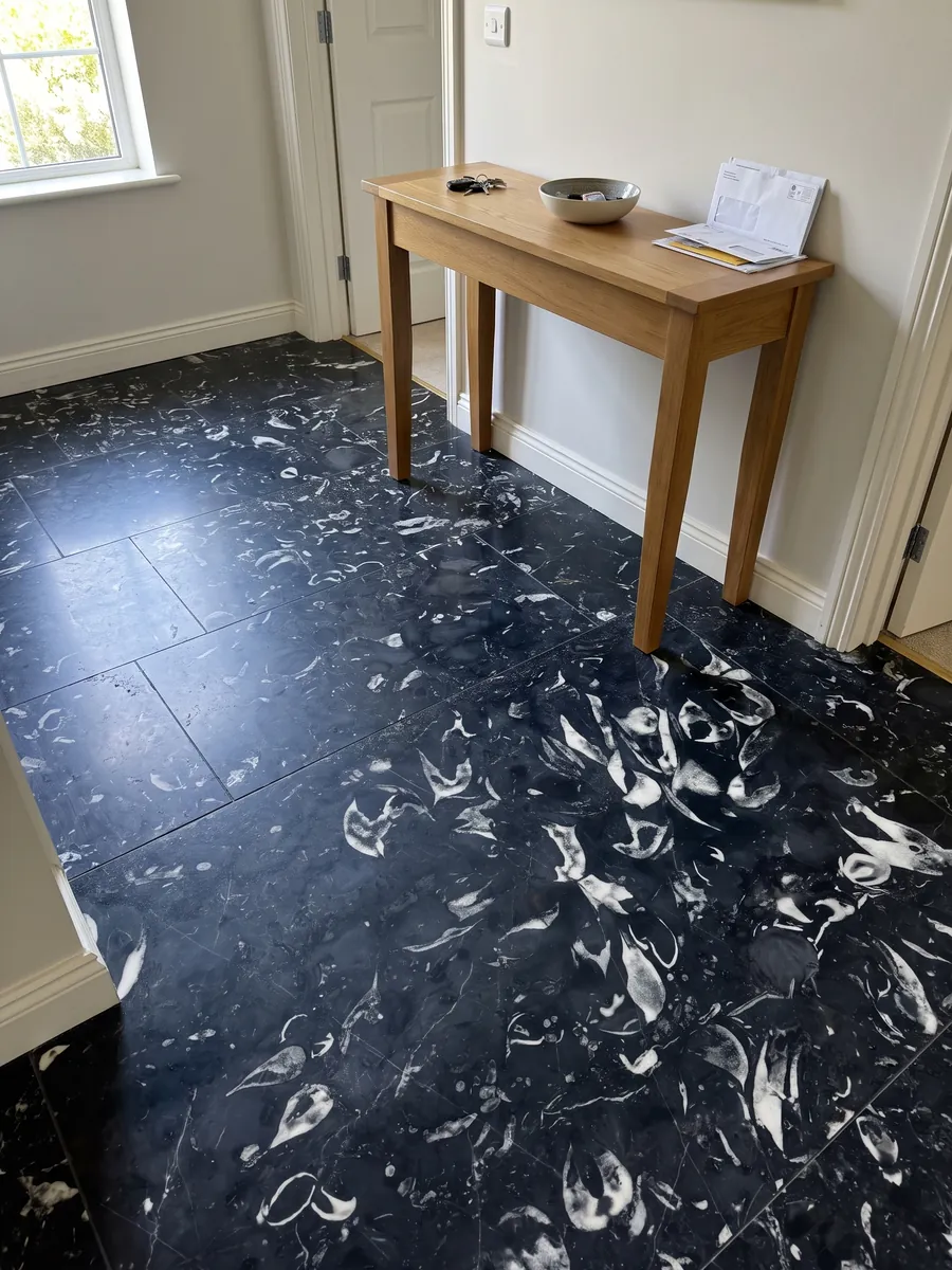 Piso de recibidor en placas grandes de Mármol Negro Boreale con luz natural: negro azulado con conchas fósiles blancas curvas bien visibles