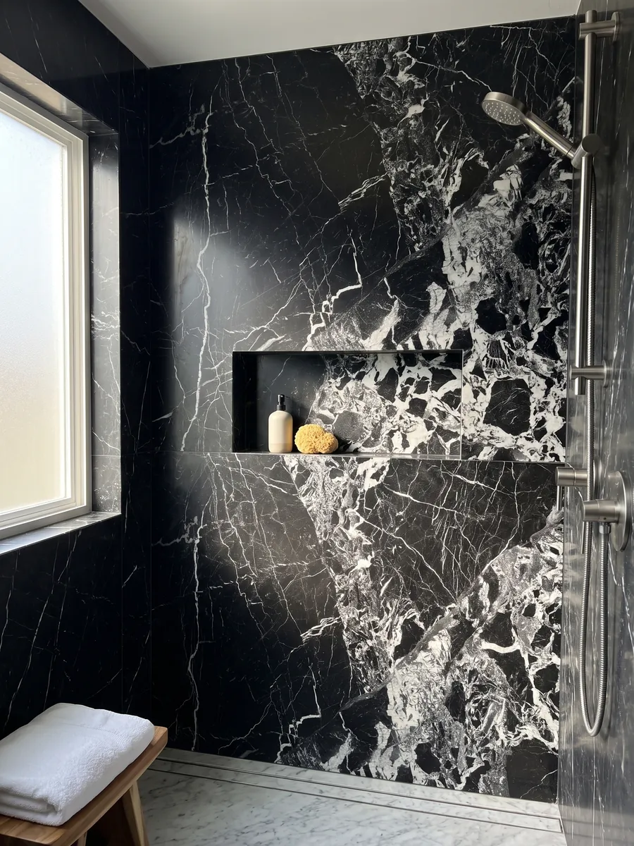 Ducha revestida con placas enteras de mármol negro Grand Antique con nicho empotrado: negro intenso con una zona de fragmentos blancos rotos que ocupa un lado de la placa