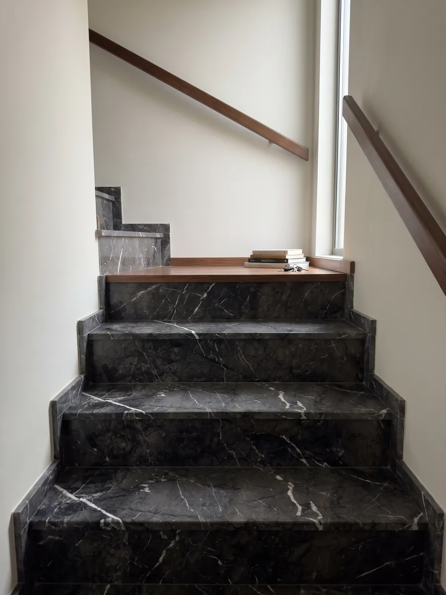 Escalera interior con peldaños de mármol negro Grigio Carnico con pasamanos: negro grisáceo con vetas blancas finas y nítidas que se ramifican