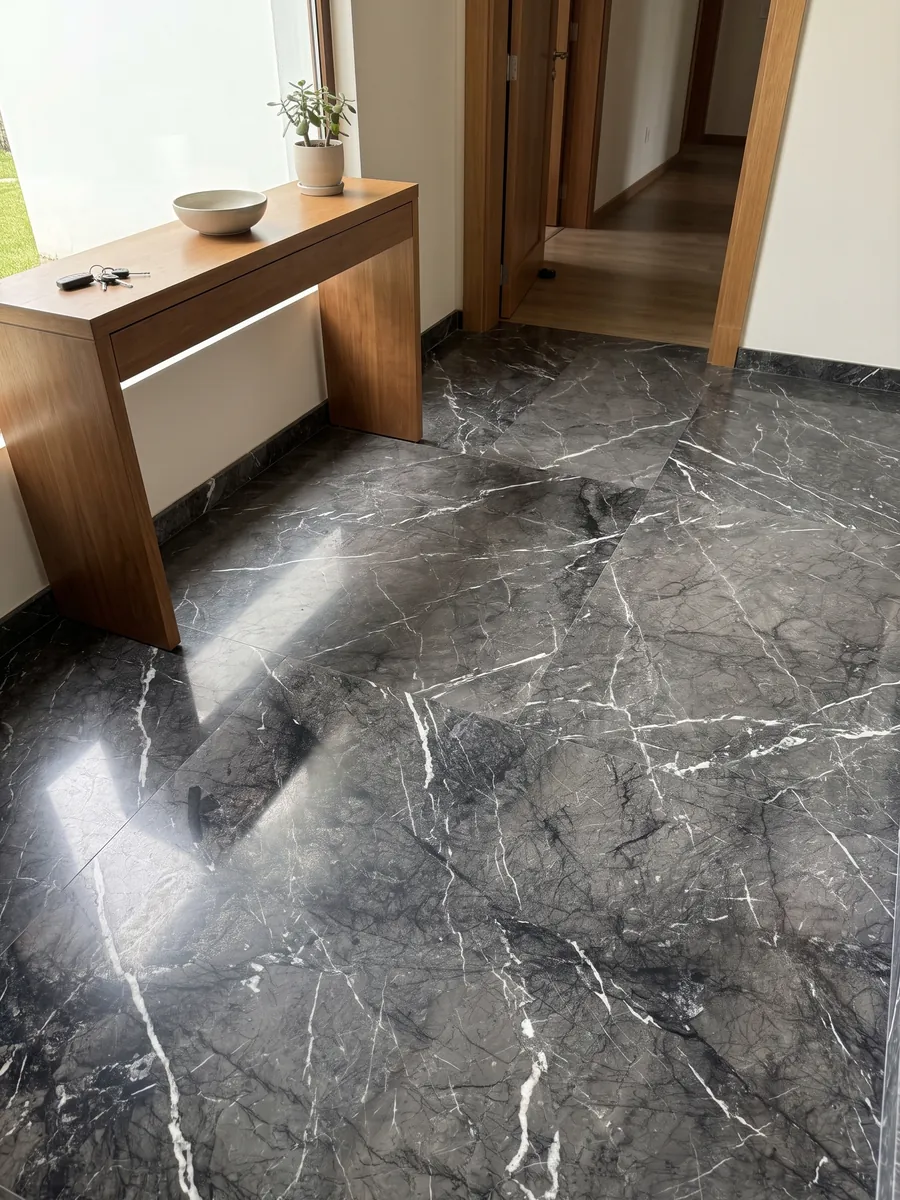 Piso de recibidor en placas grandes de mármol negro Grigio Carnico con luz natural: negro grisáceo con vetas blancas finas y nítidas que se ramifican