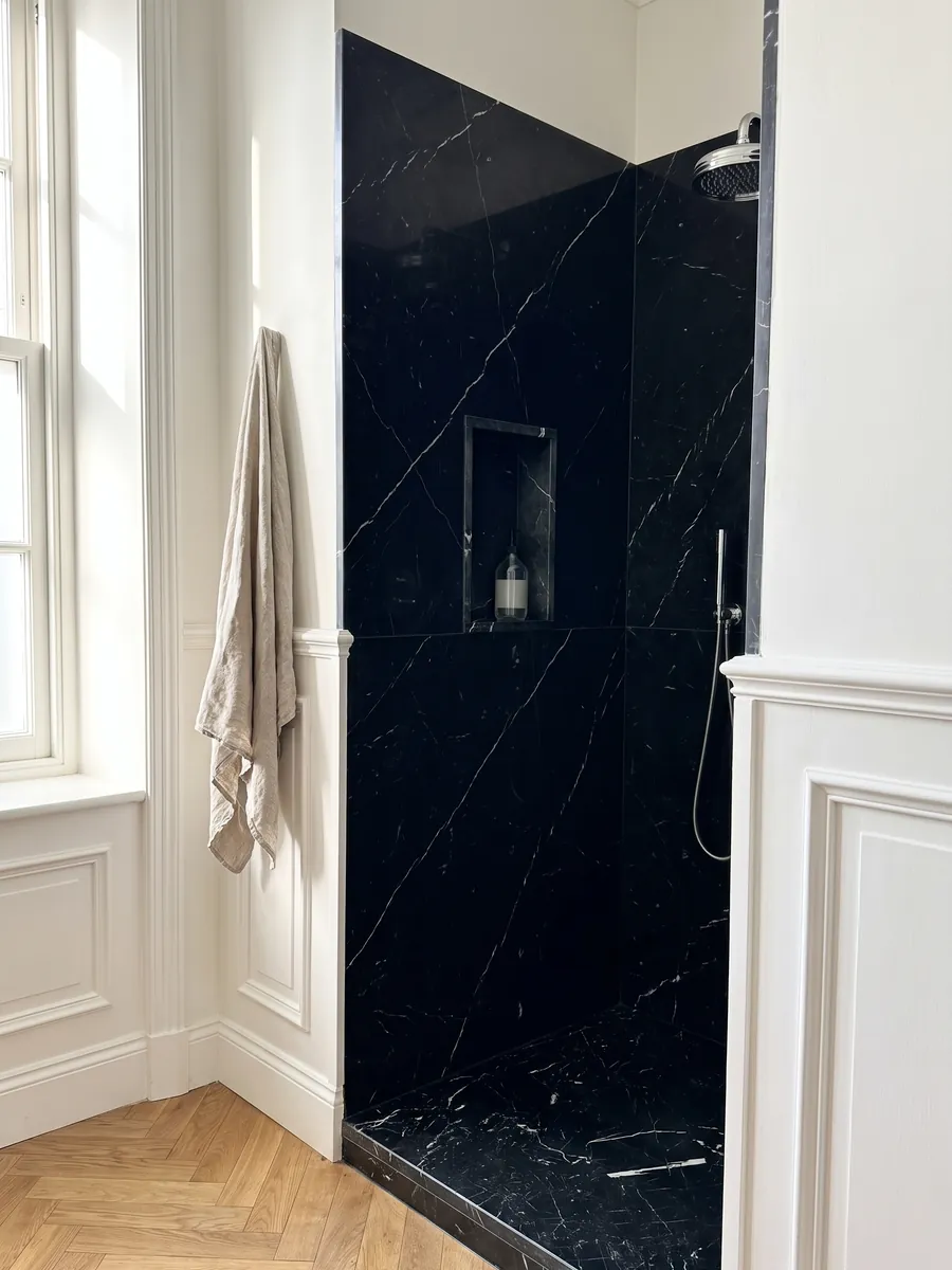 Ducha revestida con placas enteras de mármol negro Nero Marquina con nicho empotrado: negro profundo con pocas vetas blancas finas y rectas