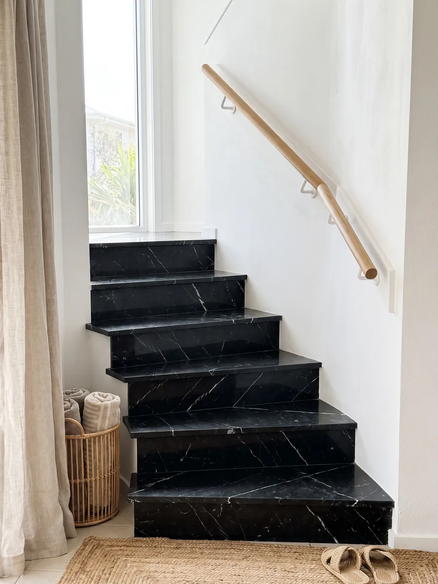 Escalera interior con peldaños de mármol negro Nero Marquina con pasamanos: negro profundo con pocas vetas blancas finas y rectas