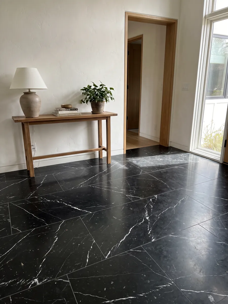 Piso de recibidor en placas grandes de mármol negro Nero Marquina con luz natural: negro profundo con pocas vetas blancas finas y rectas