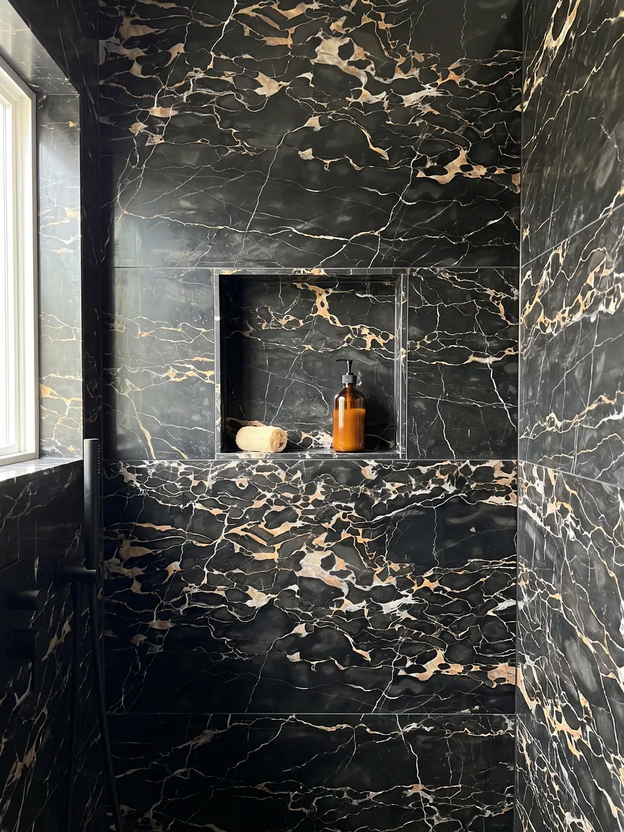 Ducha revestida con placas enteras de mármol negro Nero Portoro con nicho empotrado: negro con una red densa de vetas doradas y blancas