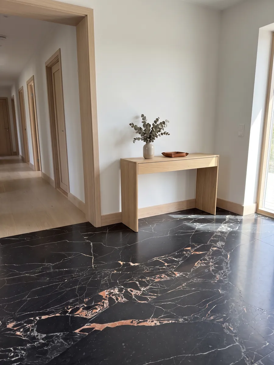 Piso de recibidor en placas grandes de mármol negro Orange Black con luz natural: negro con vetas blancas finas y manchas naranja salmón agrupadas