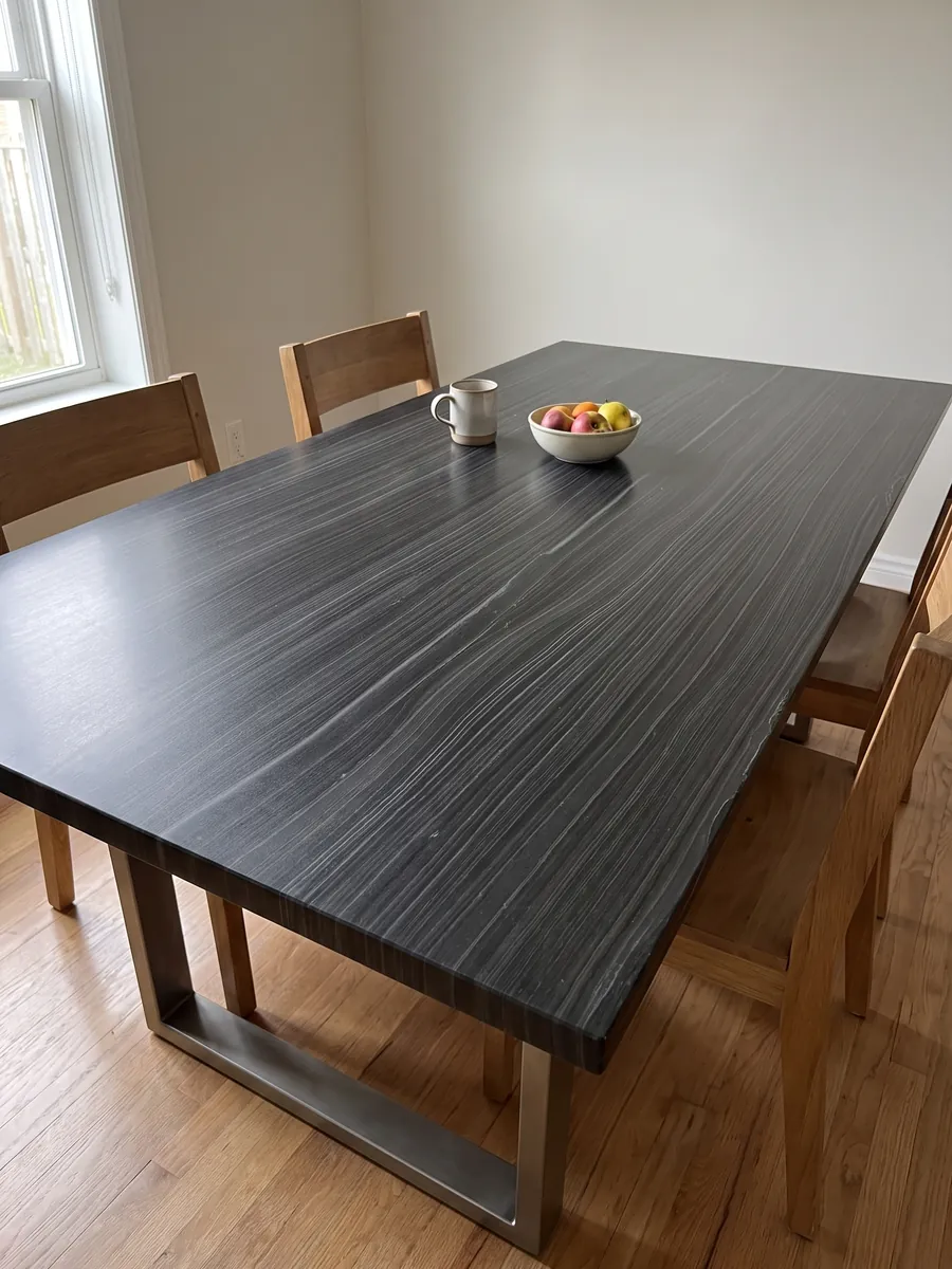 Mesa de comedor con cubierta de Mármol Negro Pagoda sobre base de acero: negro con finas líneas grises horizontales y paralelas, casi como madera
