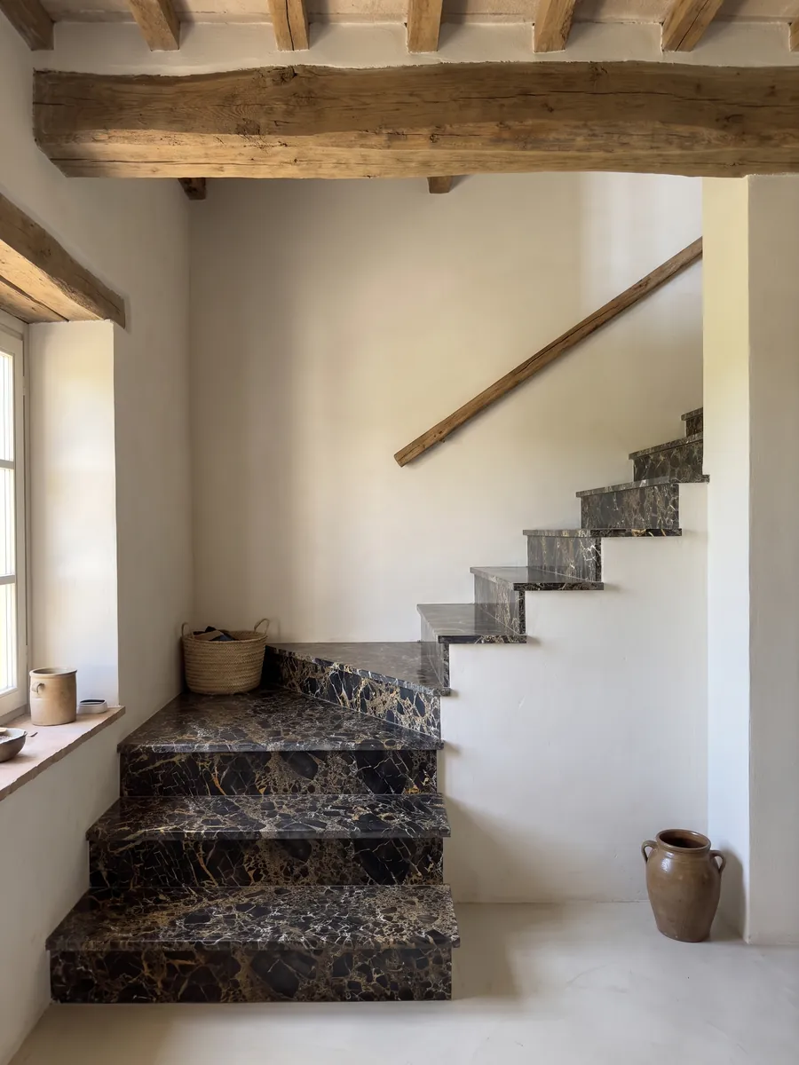 Escalera interior con peldaños de mármol negro Portoro con pasamanos: fragmentos negros envueltos por una red densa de vetas doradas y blancas