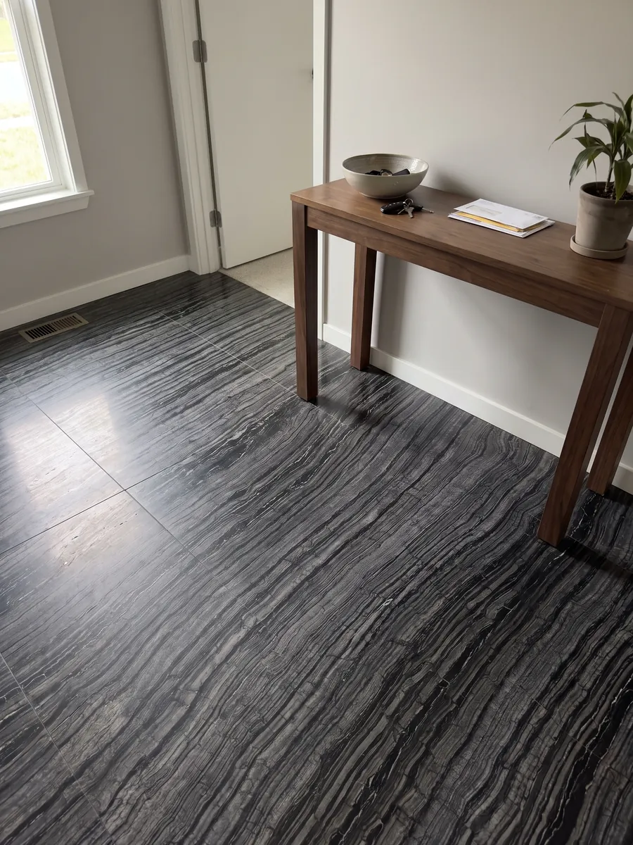 Piso de recibidor en placas grandes de mármol negro Zebrato con luz natural: negro con rayas finas onduladas grises que corren en diagonal, efecto de corteza