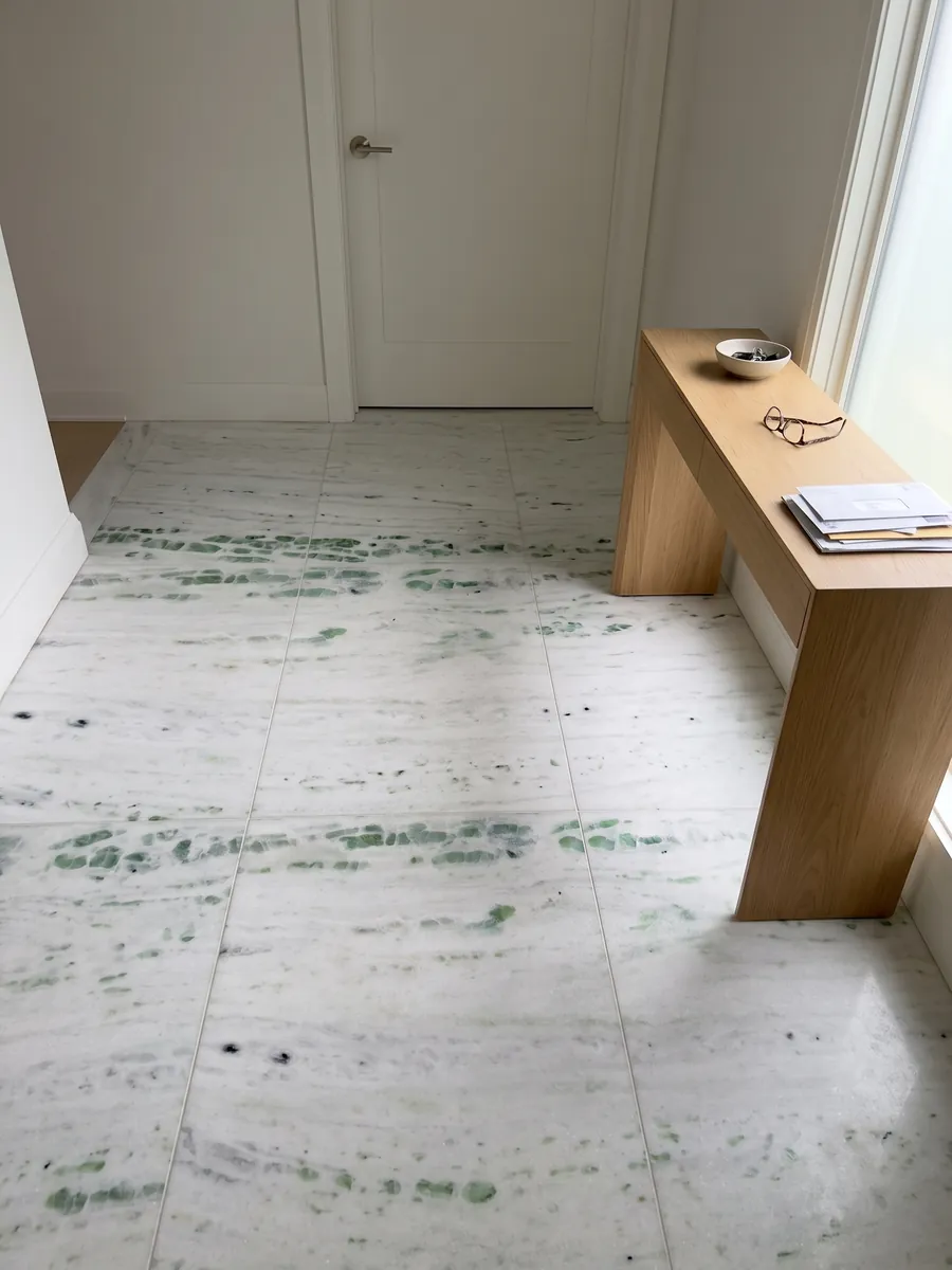 Piso de recibidor en placas grandes de Mármol Pinta Verde con luz natural: blanco con franjas horizontales salpicadas de manchas verde esmeralda