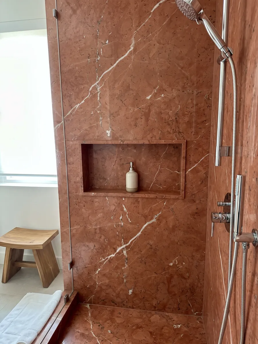 Ducha revestida con placas enteras de Mármol Rojo Alicante con nicho empotrado: rojo terracota parejo cruzado por pocas vetas blancas en diagonal