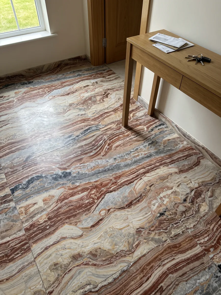 Piso de recibidor en placas grandes de mármol rojo Arabescato Rosso con luz natural: bandas horizontales onduladas rojo ladrillo, crema y gris, con manchas negras arriba