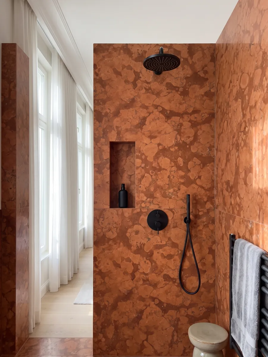 Ducha revestida con placas enteras de Mármol Rojo Asiago con nicho empotrado: naranja rojizo con manchas redondeadas claras sobre fondo más oscuro