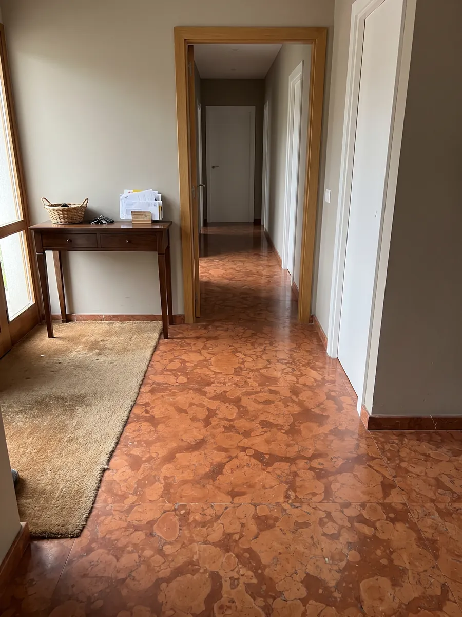 Piso de recibidor en placas grandes de Mármol Rojo Asiago con luz natural: naranja rojizo con manchas redondeadas claras sobre fondo más oscuro