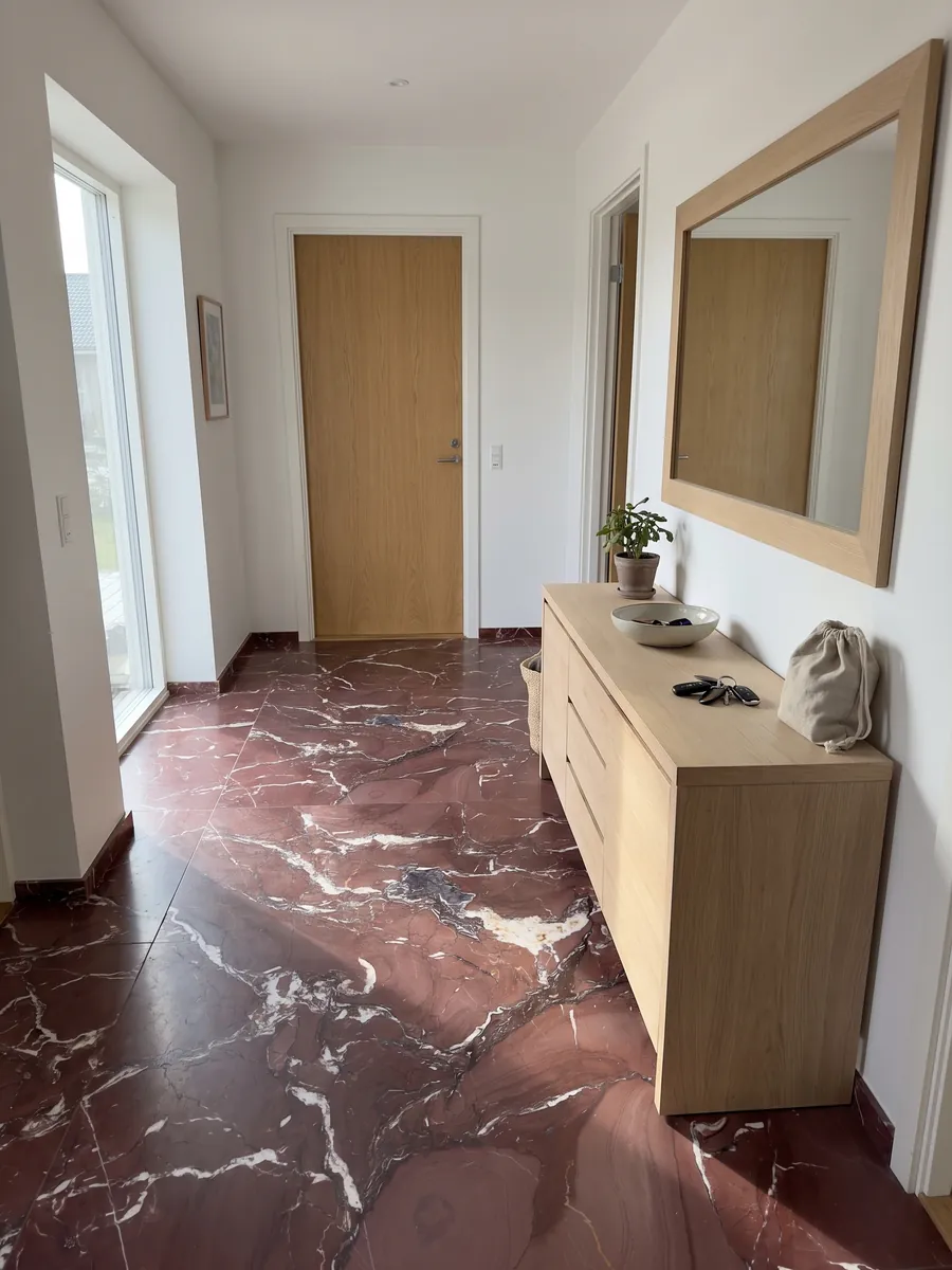Piso de recibidor en placas grandes de Mármol Rojo Cardinale con luz natural: rojo burdeos con vetas blancas irregulares y algunas manchas gris violáceo
