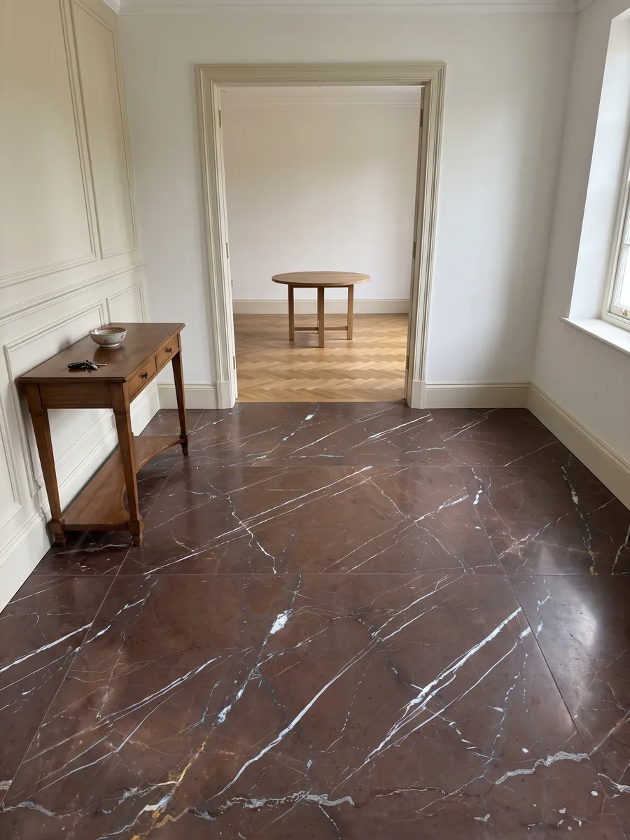 Piso de recibidor en placas grandes de Mármol Rojo Collemandina con luz natural: marrón rojizo oscuro con vetas blancas finas, rectas y paralelas en diagonal