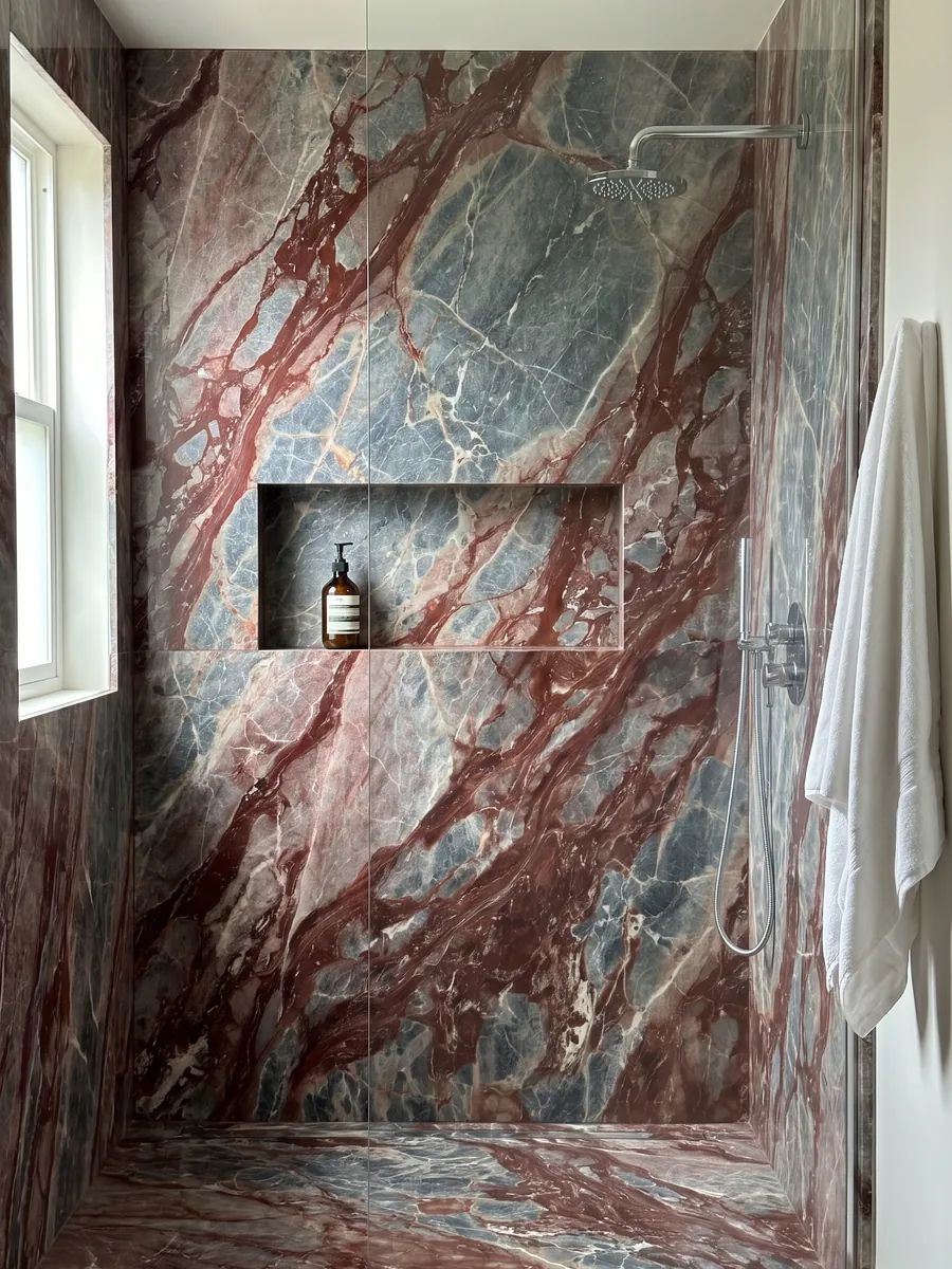 Ducha revestida con placas enteras de mármol rojo Domus Red con nicho empotrado: fragmentos gris azulado unidos por vetas y manchas rojo vino