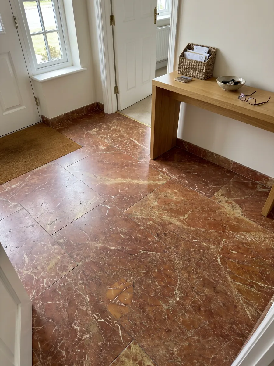 Piso de recibidor en placas grandes de mármol rojo Melograno con luz natural: rojo ladrillo amarronado con red fina de vetas claras y zonas ocre