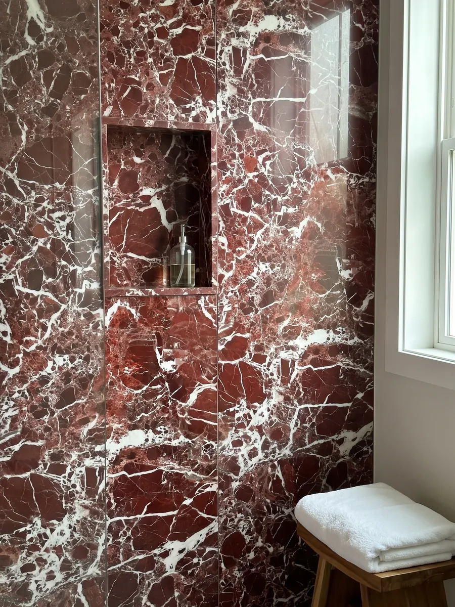 Ducha revestida con placas enteras de mármol rojo Rosso Lepanto con nicho empotrado: fragmentos rojo intenso rodeados por una red densa de vetas blancas