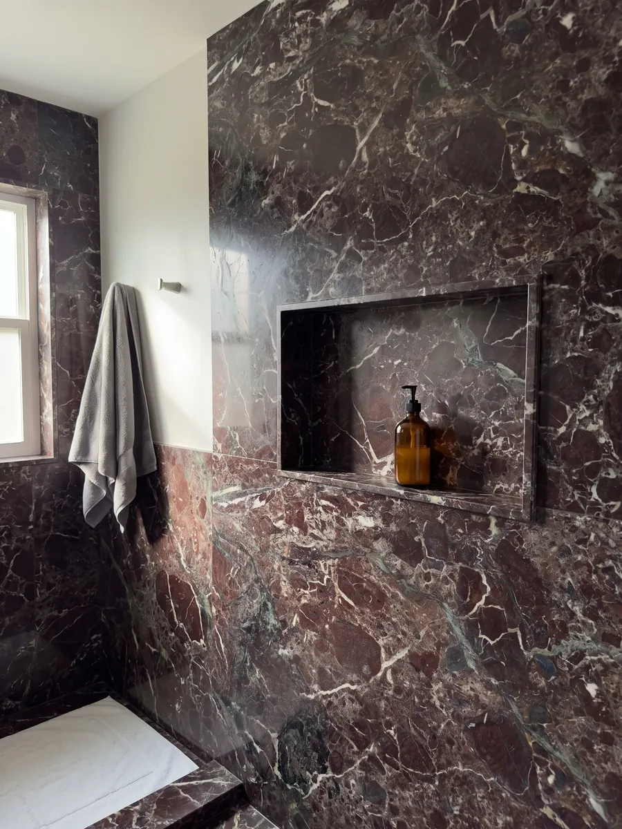 Ducha revestida con placas enteras de mármol rojo Rosso Levanto con nicho empotrado: burdeos oscuro con zonas verde grisáceo y una red de vetas blancas