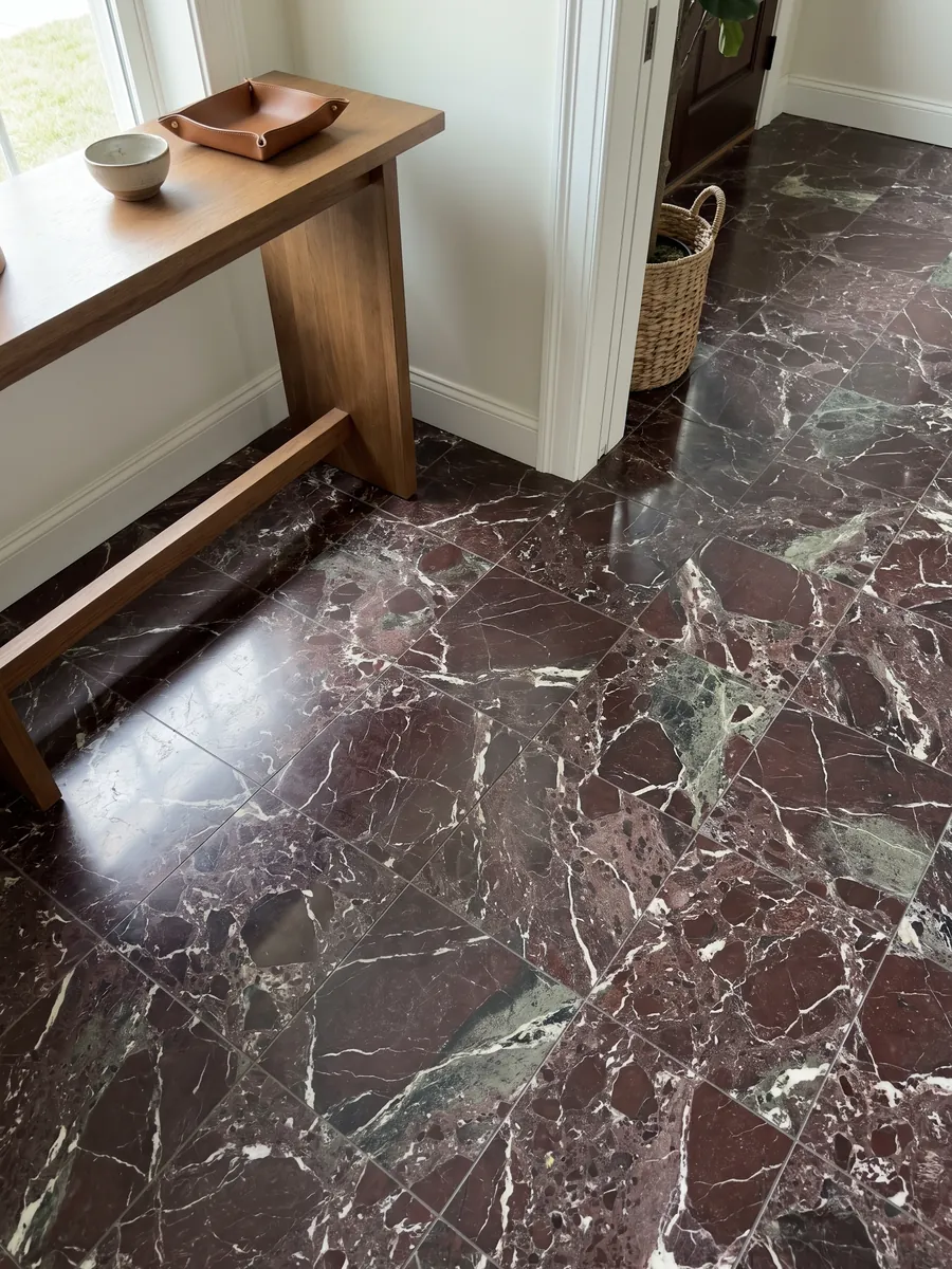 Piso de recibidor en placas grandes de mármol rojo Rosso Levanto con luz natural: burdeos oscuro con zonas verde grisáceo y una red de vetas blancas