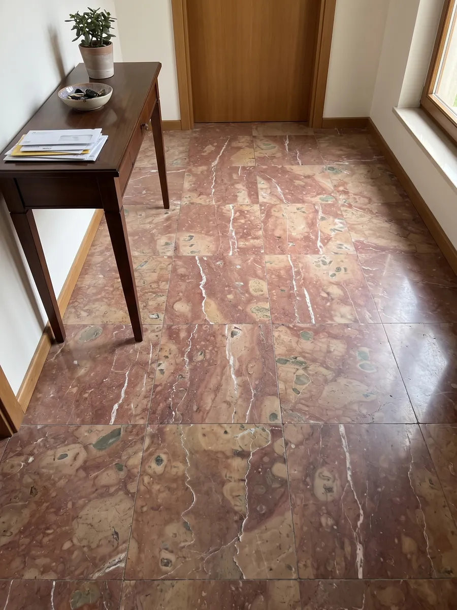 Piso de recibidor en placas grandes de mármol rojo Rosso Verona con luz natural: rojo violáceo con manchas beige y dos vetas blancas verticales irregulares